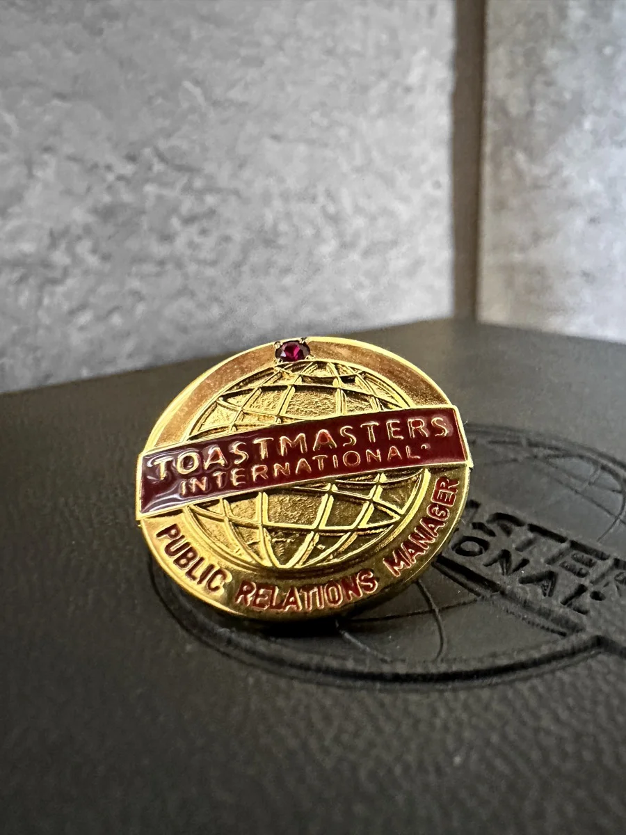 Marie Feutrier wearing Toastmasters Public Relations Manager badge with pride
